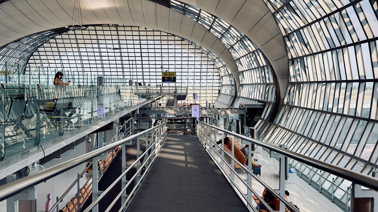 Long terminal concourse with passengers walking between gates under a high ceiling